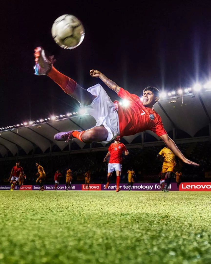 Soccer player in red jersey performing overhead kick under stadium floodlights during night match